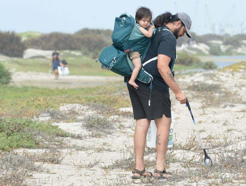 A father and son pick up garbage around Ormond Lagoon during the Coastal Cleanup Day in 2022.