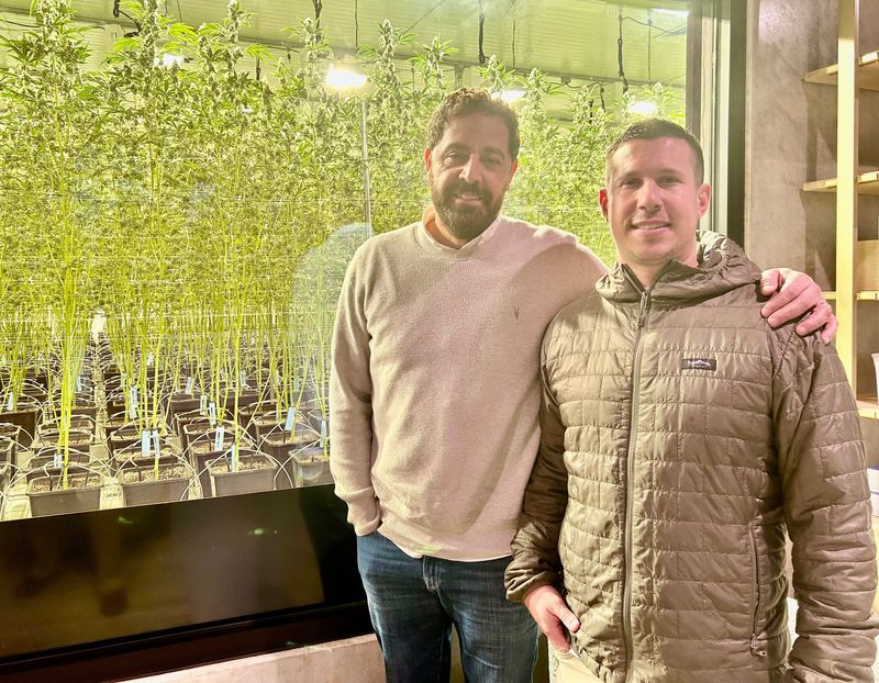 A Golden State managing partners Simmon Saraf, left, and Robert "Bear" Masterson stand in front a large window that shows one of its cannabis strains that the business grows in-house.