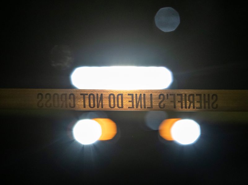 The lights from a Riverside County Sheriff's Department vehicle light up crime scene tape at the Aquatic Center in Palm Desert, Calif., Saturday, Sept. 14, 2024.