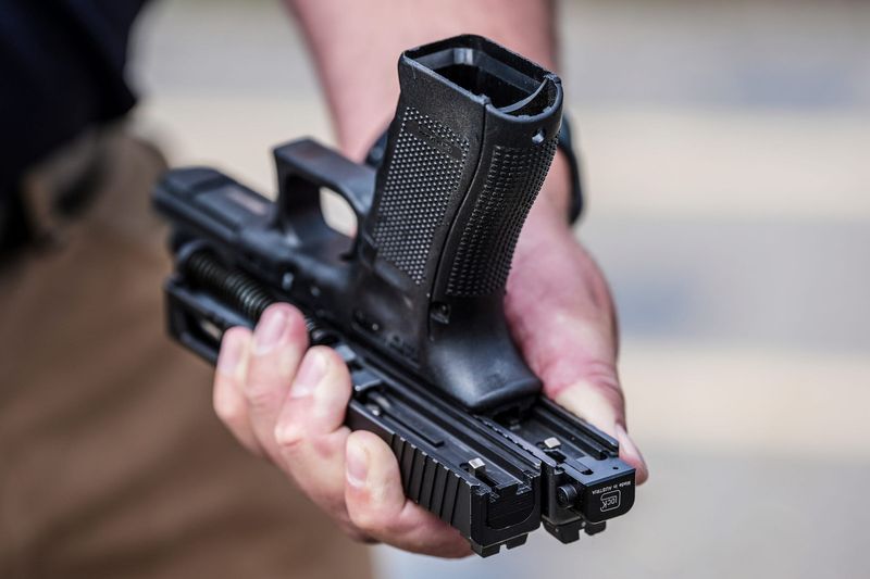 Special Agent Kenton Weston holds two Glock handgun slides, one with a machine gun conversion switch, right, and one without, during a demonstration on the danger of such devices that make handguns fully automatic at the Canton Police Department training facility in Canton on Tuesday, July 23, 2024.