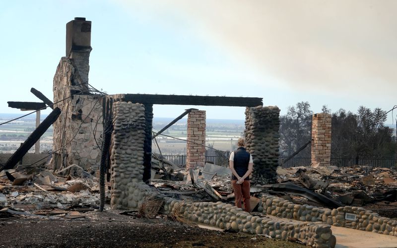 A person observes a burned house in the Camarillo Heights neighborhood on Thursday, Nov. 7, 2024, a day after the Mountain Fire swept through the area.