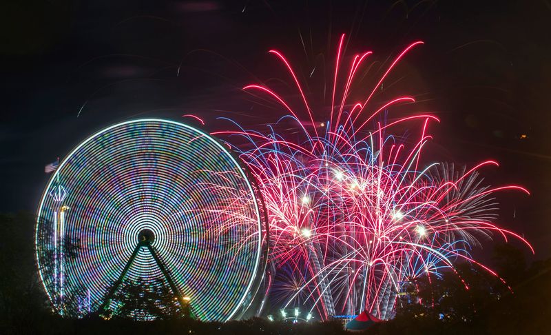 Fireworks explode in the air beyond a Ferris wheel on the midway for the California State Fair at Cal Expo in Sacramento on Jul. 21, 2017.