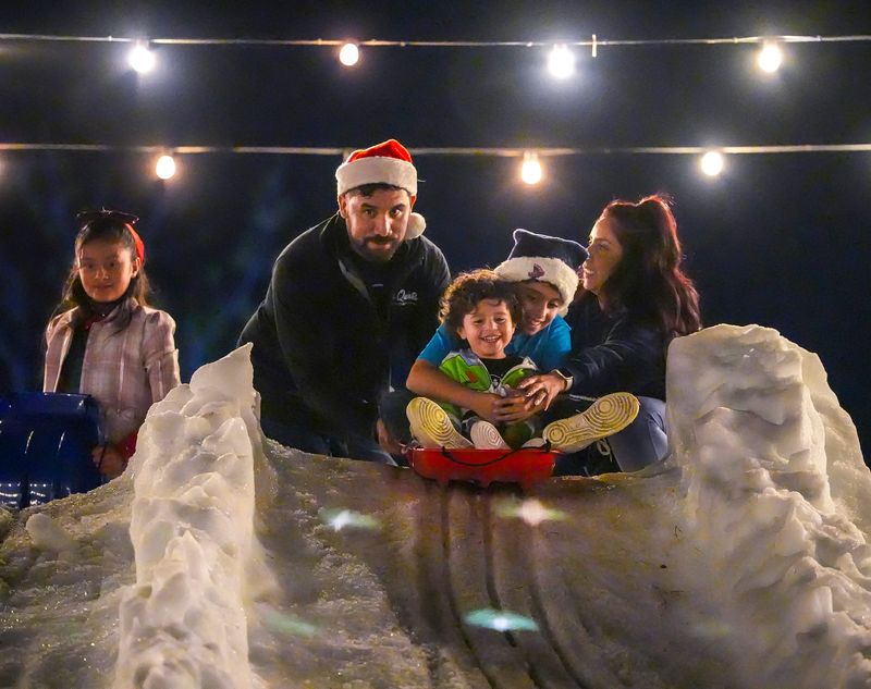 11-year-old Kaden Matcham of Indio holds on to his 2-year-old brother Kamrin Perea as they sled down a hill of snow brought in for the La Quinta's annual tree lighting in La Quinta, Calif., Friday, Dec. 6, 2024.