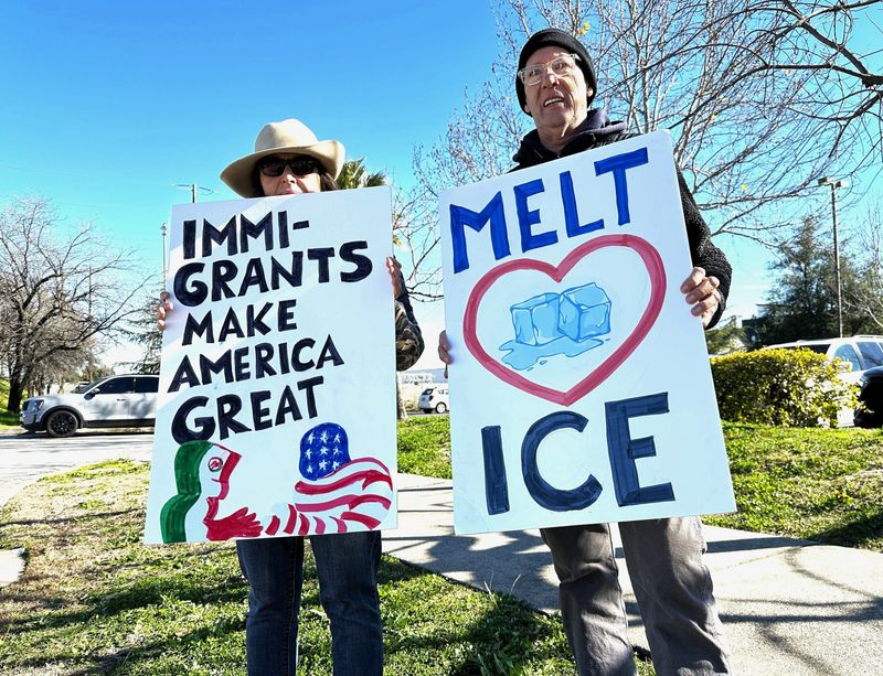Brooke McGowen, left, and Heinz Patatzki show signs to motorists during an anti-Trump demonstration at the intersection of Court Street and Eureka Way in Redding on Saturday, Feb. 8, 2025.