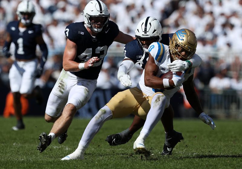 Oct 5, 2024; University Park, Pennsylvania, USA; UCLA Bruins running back Jalen Berger (0) runs with the ball before being tackled by Penn State Nittany Lions defensive end Abdul Carter (11) during the third quarter at Beaver Stadium. Mandatory Credit: Matthew O'Haren-Imagn Images