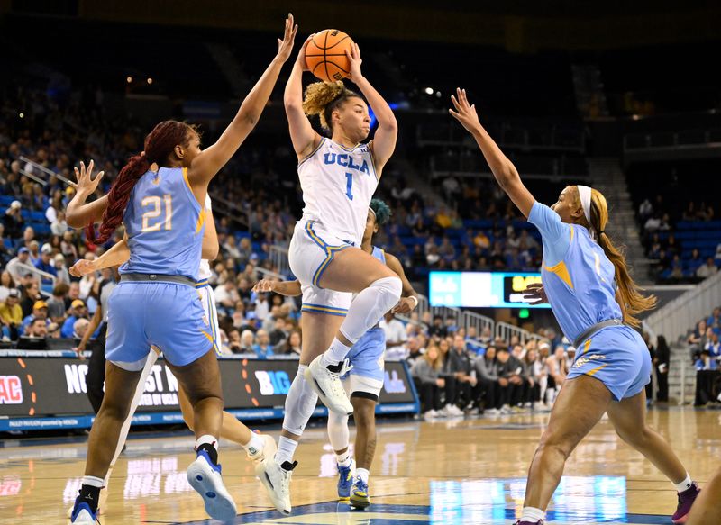 Mar 21, 2025; Los Angeles, California, USA; UCLA Bruins guard Kiki Rice (1) hangs in the air while passing the ball between Southern Lady Jaguars center Tionna Lidge (21) and Southern Lady Jaguars guard Aniya Gourdine (1) in the first quarter of an NCAA Tournament first-round game at Pauley Pavilion presented by Wescom. Mandatory Credit: Robert Hanashiro-Imagn Images
