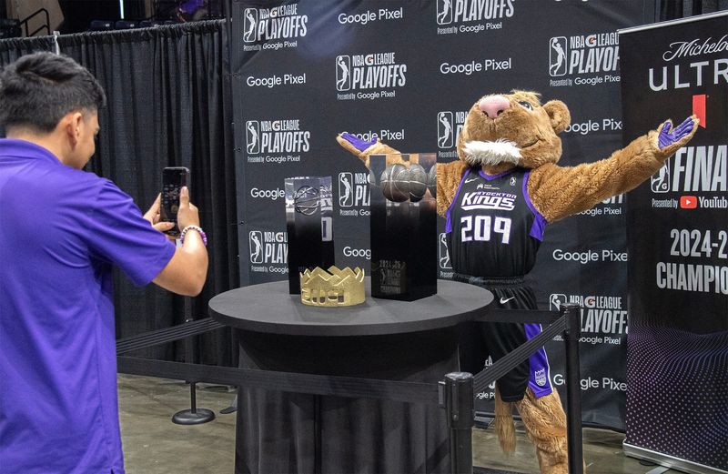 Stockton Kings mascot Dunkston poses for a picture with the NBA G League Western Conference, left, and G League Championship trophies on display at the Adventist Health Arena for a celebration event for the King’s win in the NBA G League Championship.