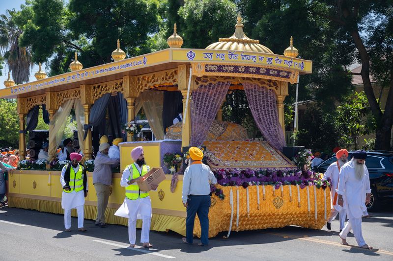A brightly colored float carrying the Sikh holy book makes its way down the street during the Stockton Gurdwara or Sikh Temple’s annual Nagar Kirtan parade on San Joaquin Street near Worth Street in south Stockton on Apr. 20, 2025. The parade starts at the Stockton Gurdwara Sahib, or Sikh Temple, goes to downtown and then back to the temple. Free food is offered to participants and onlookers along the parade route. The parade, which can draw up to 20,000 people, celebrates the spring observance of Vaisakhi, an important Sikh holiday.