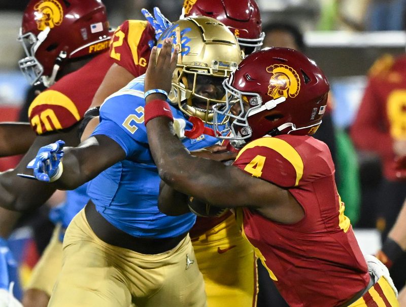 Nov 23, 2024; Pasadena, California, USA; UCLA Bruins linebacker Oluwafemi Oladejo (2) tackles USC Trojans running back Woody Marks (4) during the first quarter at Rose Bowl. Mandatory Credit: Robert Hanashiro-Imagn Images