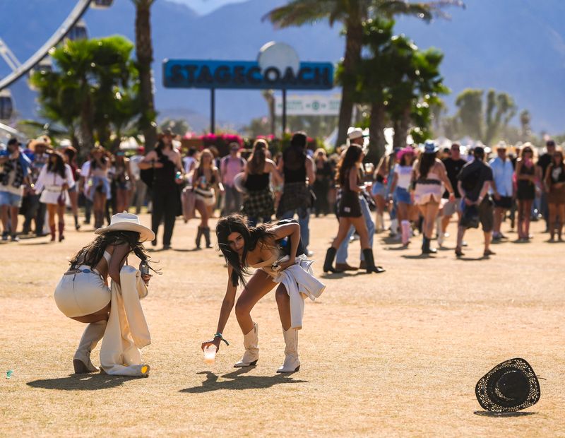 Jasmine Ruiz of San Diego puts down her drink to chase after her hat as it blows away in the wind at the Stagecoach country music festival in Indio, Calif., Saturday, April 26, 2025.
