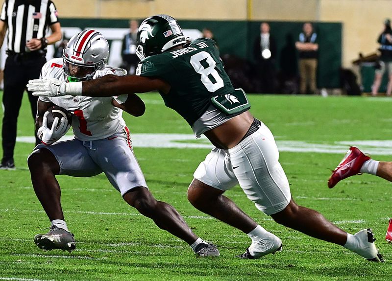 Sep 28, 2024; East Lansing, Michigan, USA; Michigan State Spartans defensive lineman Anthony Jones (8) tackles Ohio State Buckeyes wide receiver Jeremiah Smith (4) in the first quarter at Spartan Stadium. Mandatory Credit: Dale Young-Imagn Images
