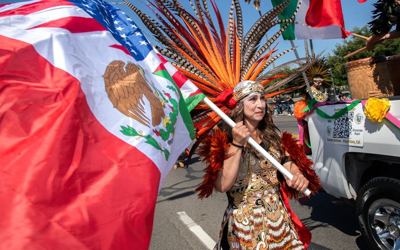 Sonia Soto carries a flag with the Danza Azteca Huitzitzilin Olin dance group as they make their way down Weber Avenue in the annual Cinco De Mayo Parade in downtown Stockton on May 4, 2025.