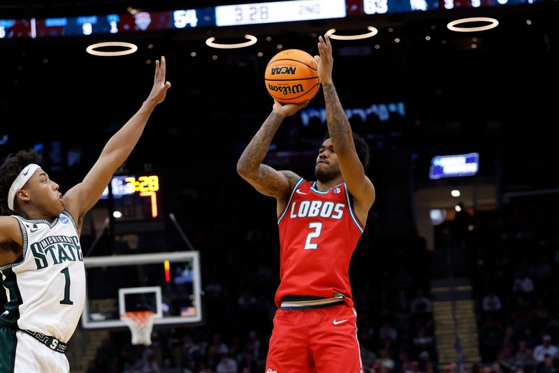 Mar 23, 2025; Cleveland, OH, USA; New Mexico Lobos guard Donovan Dent (2) shoots the ball over Michigan State Spartans guard Jeremy Fears Jr. (1) in the second half during the NCAA Tournament Second Round at Rocket Arena. Mandatory Credit: Rick Osentoski-Imagn Images