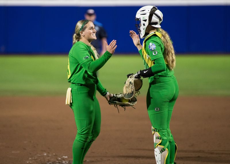 May 29, 2025; Oklahoma City, OK, USA; Oregon Ducks pitcher Lyndsey Grein (33) and Oregon Ducks catcher Emma Cox (21) slap hands in the first inning during the NCAA Softball Women's College World Series at Devon Park. Mandatory Credit: Brett Rojo-Imagn Images