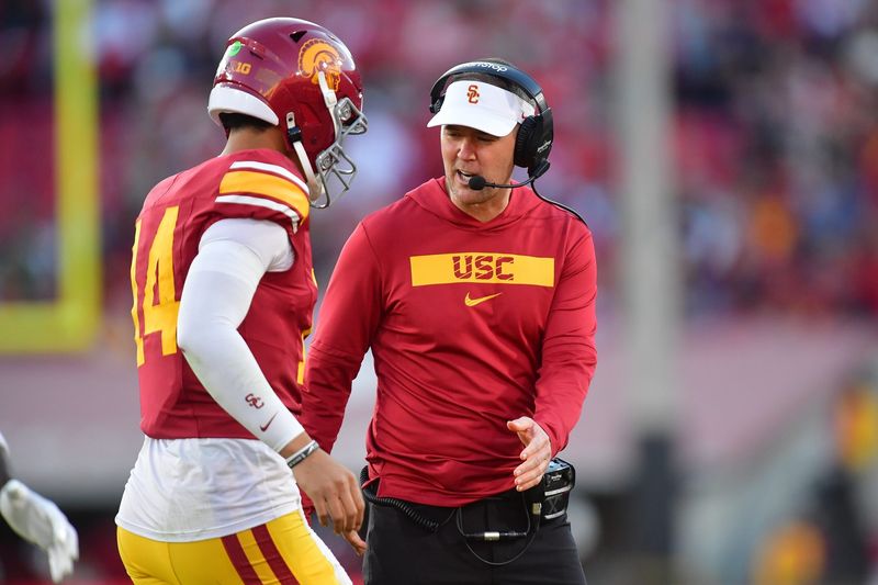 Nov 16, 2024; Los Angeles, California, USA; Southern California Trojans head coach Lincoln Riley greets quarterback Jayden Maiava (14) after scoring a touchdown against the Nebraska Cornhuskers during the second half at the Los Angeles Memorial Coliseum. Mandatory Credit: Gary A. Vasquez-Imagn Images