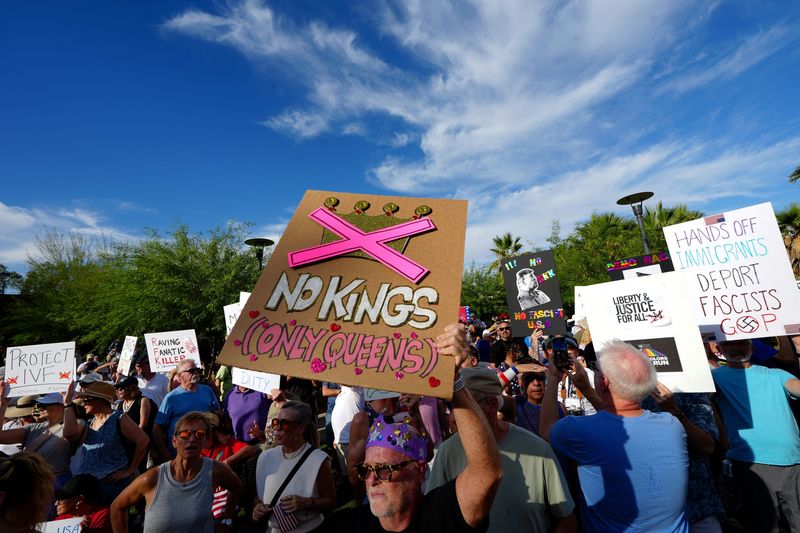 Tom Dolle, center, of Palm Springs holds a sign during a No Kings protest in downtown Palm Springs, Calif., on Saturday, June 14, 2025.
