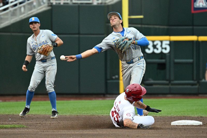 Jun 17, 2025; Omaha, Neb, USA; UCLA Bruins shortstop Roch Cholowsky (1) completes a double play after getting Arkansas Razorbacks designated hitter Kuhio Aloy (25) out during the first inning at Charles Schwab Field. Mandatory Credit: Steven Branscombe-Imagn Images