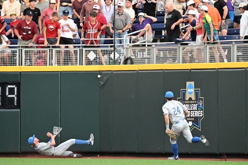 Jun 17, 2025; Omaha, Neb, USA; UCLA Bruins right fielder A.J. Salgado (24) and UCLA Bruins center fielder Payton Brennan (11) play a ball off the wall against the Arkansas Razorbacks during the fifth inning at Charles Schwab Field. Mandatory Credit: Steven Branscombe-Imagn Images