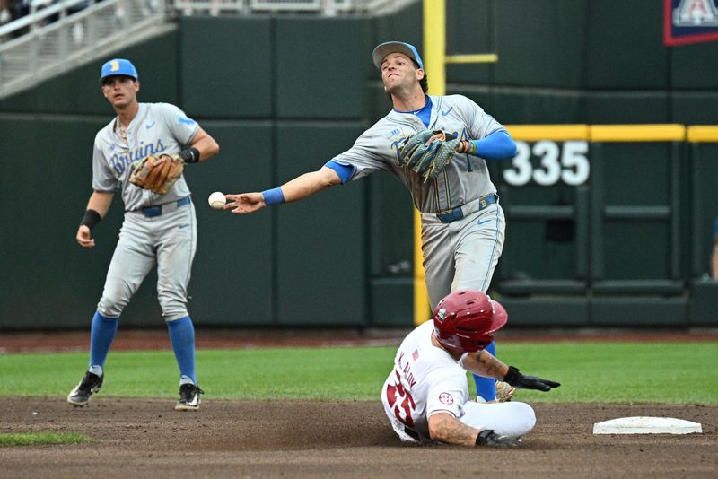 Jun 17, 2025; Omaha, Neb, USA; UCLA Bruins shortstop Roch Cholowsky (1) completes a double play after getting Arkansas Razorbacks designated hitter Kuhio Aloy (25) out during the first inning at Charles Schwab Field. Mandatory Credit: Steven Branscombe-Imagn Images