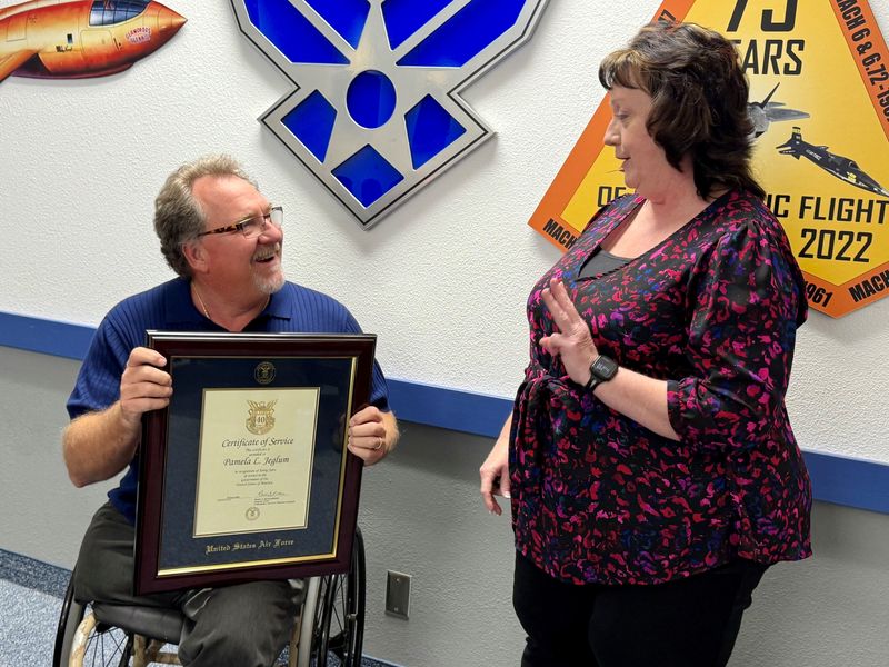 Pam Jeglum motions to co-worker Dan Osburn that she wants to work three more years before retirement from the U.S. Air Force.