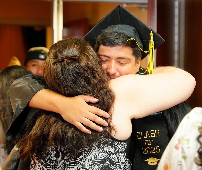 Marco Carrera of San Jacinto High School gets a hug from one of his teachers after the Palm Springs Unified School District summer graduation ceremony at Palm Springs High School, July 9, 2025.