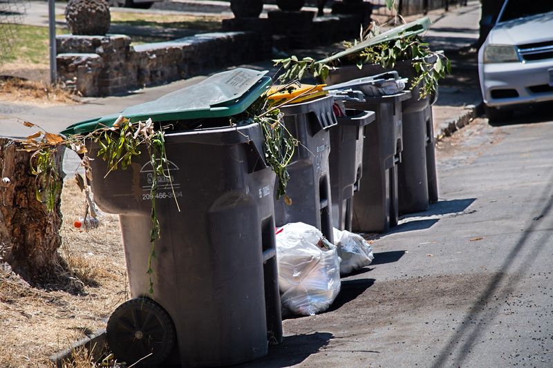 Trash overflows from bins on Poplar and Commerce streets in Stockton on Jul. 17, 2025.