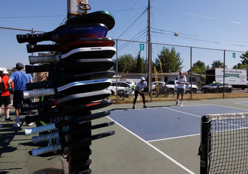 Players wedge their rackets in a queue system for the next court at the Westmoreland Pickleball Court on July 18, 2025, in Eugene.