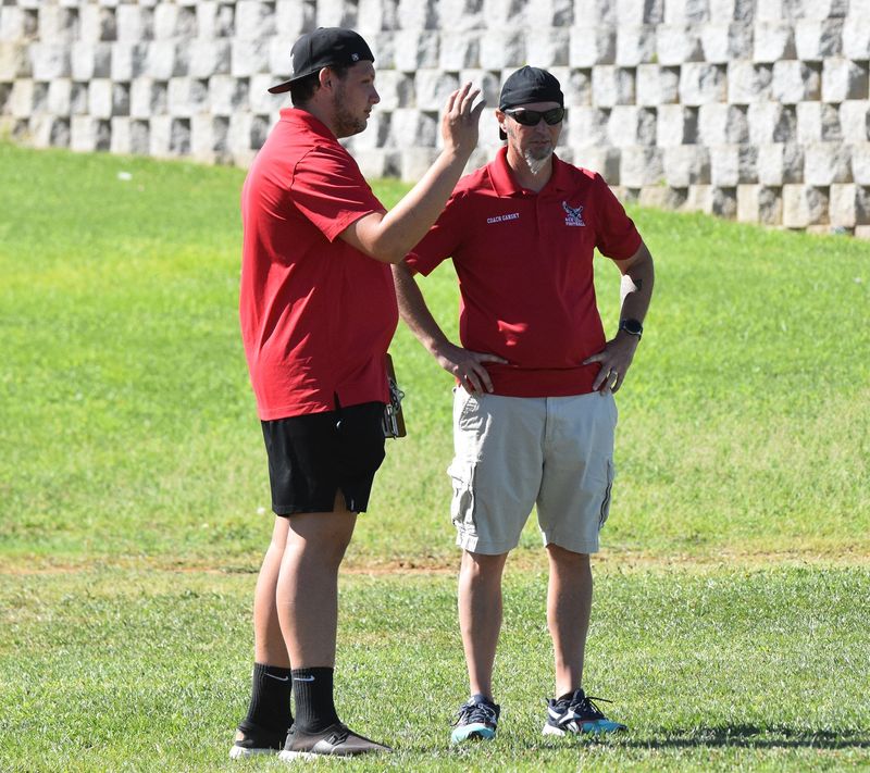 The Academy of Careers and Exploration head coach Aaron Gansky, right, chats with Austin Dashiell during a recent summer practice at the school.