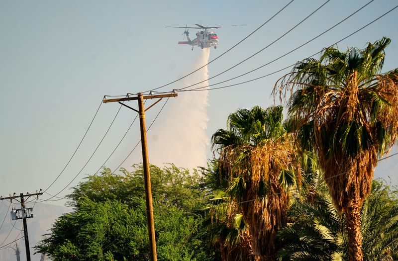 People walk along Ave 54 during the Shady Fire in Coachella and Thermal, Calif., July 25, 2025.