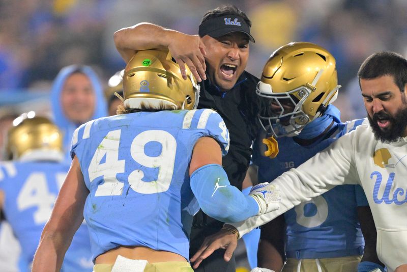 Nov 8, 2024; Pasadena, California, USA; UCLA Bruins defensive coordinator Ikaika Malloe, center, celebrates with linebacker Carson Schwesinger (49) defensive back Jaylin Davies (6) after an interception in the second half against the Iowa Hawkeyes at the Rose Bowl. Mandatory Credit: Jayne Kamin-Oncea-Imagn Images