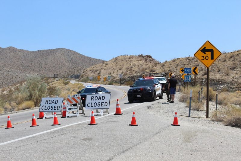 A man speaks with a law enforcement officer at the gated entryway to Highway 74 at the base of the mountains near Palm Desert on Wednesday, Aug. 6. The road has been fully closed since the Rosa Fire broke out two days earlier.