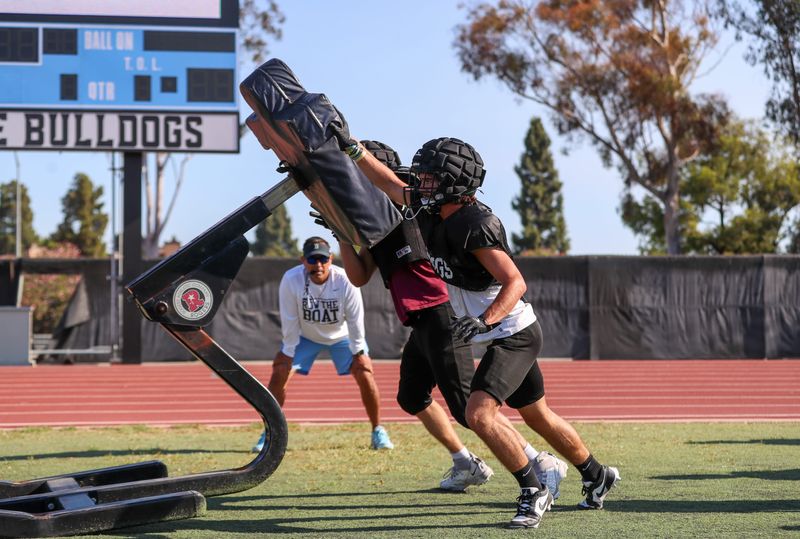 Offensive coordinator Anthony Morales watches senior tight end and defensive end Andrew Silva work a drill on a blocking sled alongside a teammate during a Buena High football practice on Aug. 7, 2025, in Ventura.