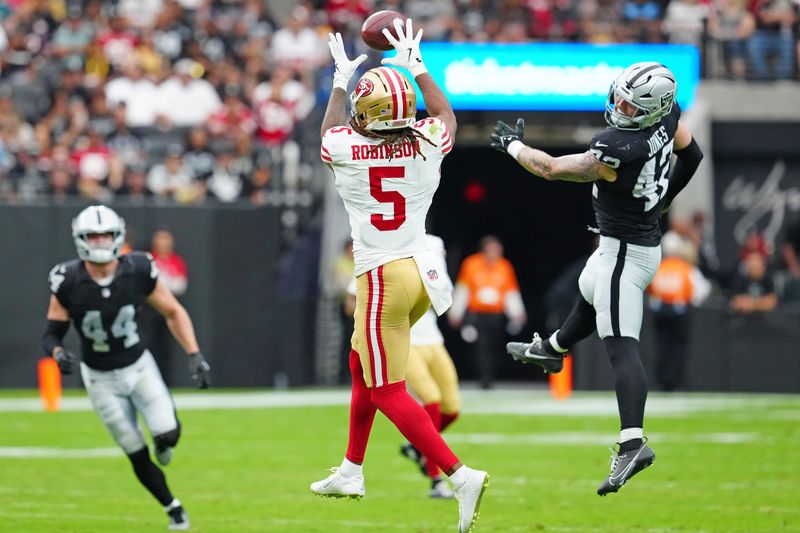 Aug 16, 2025; Paradise, Nevada, USA; San Francisco 49ers wide receiver Demarcus Robinson (5) makes a catch behind Las Vegas Raiders linebacker Matt Jones (42) during the second quarter at Allegiant Stadium. Mandatory Credit: Stephen R. Sylvanie-Imagn Images