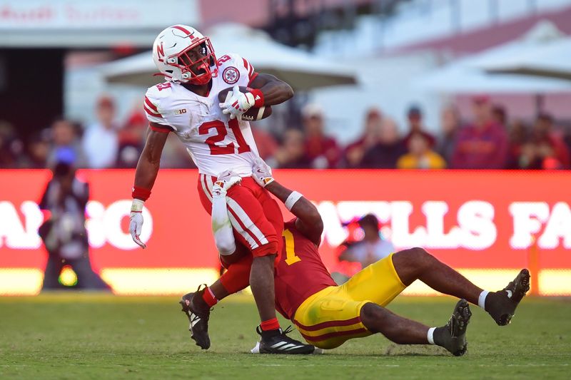 Nov 16, 2024; Los Angeles, California, USA; Nebraska Cornhuskers running back Emmett Johnson (21) is brought down by Southern California Trojans safety Kamari Ramsey (7) during the second half at the Los Angeles Memorial Coliseum. Mandatory Credit: Gary A. Vasquez-Imagn Images