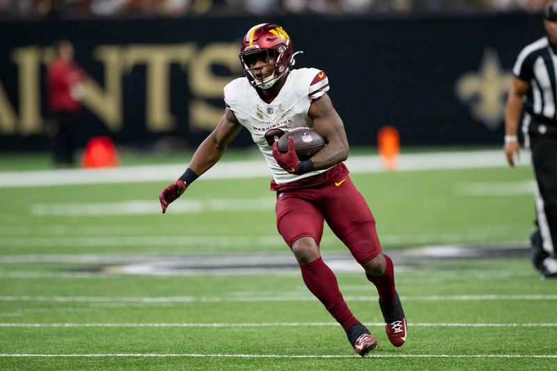 Dec 15, 2024; New Orleans, Louisiana, USA; Washington Commanders running back Brian Robinson Jr. (8) runs against the New Orleans Saints during the first half at Caesars Superdome. Mandatory Credit: Matthew Hinton-Imagn Images