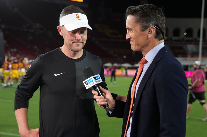 Aug 30, 2025; Los Angeles, California, USA; Big Ten Network reporter Rhett Lewis (right) interviews Southern California Trojans head coach Lincoln Riley after the game against the Missouri State Bears at United Airlines Field at Los Angeles Memorial Coliseum. Mandatory Credit: Kirby Lee-Imagn Images