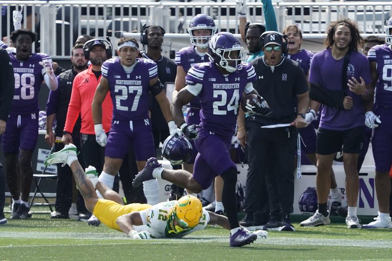Sep 13, 2025; Evanston, Illinois, USA; Oregon Ducks defensive back Peyton Woodyard (12) tries to tackle Northwestern Wildcats running back Dashun Reeder (24) as he run for a touchdown during the second half at Northwestern Medicine Field at Martin Stadium. Mandatory Credit: David Banks-Imagn Images