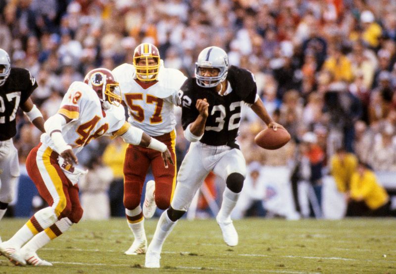 Jan 22, 1984; Tampa, FL, USA; FILE PHOTO; Los Angeles Raiders running back Marcus Allen (32) carries the ball pursued by Washington Redskins safety Ken Coffey (48) and linebacker Rich Milot (57) during Super Bowl XVIII at Tampa Stadium. The Raiders defeated the Redskins 38-9 and Allen was named Super Bowl MVP. Mandatory Credit: Manny Rubio-USA TODAY Sports