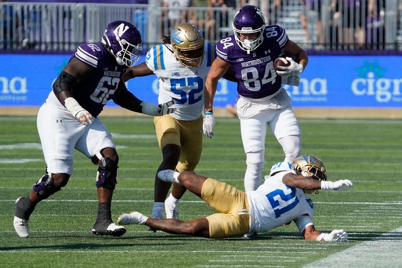 Sep 27, 2025; Evanston, Illinois, USA; Northwestern Wildcats tight end Hunter Welcing (84) catches a pass as UCLA Bruins defensive back Cole Martin (21) tries to tackle him during the first half at Northwestern Medicine Field at Martin Stadium. Mandatory Credit: David Banks-Imagn Images