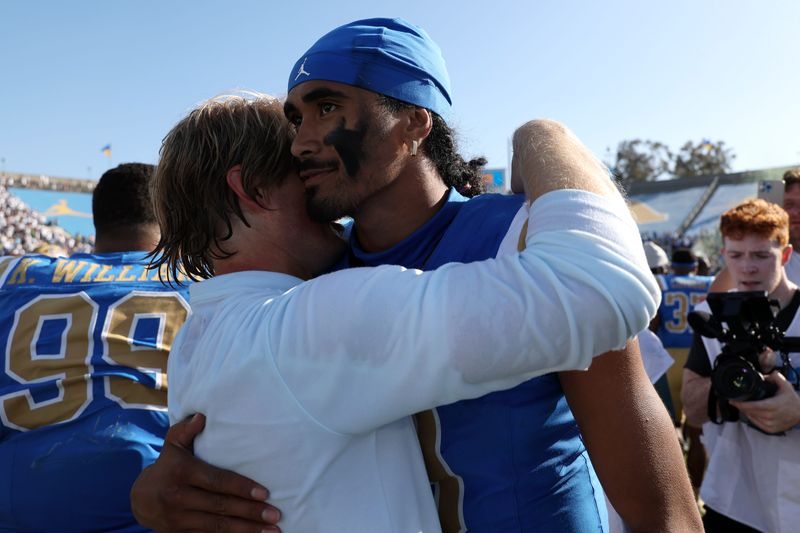 Oct 4, 2025; Pasadena, California, USA; UCLA Bruins quarterback Nico Iamaleava (9,right) hugs new offensive coordinator Jerry Neuheisel after defeating the Penn State Nittany Lions 42-37 at Rose Bowl. Mandatory Credit: Kiyoshi Mio-Imagn Images