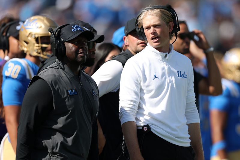 Oct 4, 2025; Pasadena, California, USA; UCLA Bruins interim head coach Tim Skipper (left) and new offensive coordinator Jerry Neuheisel (right) on the sideline during second half against the Penn State Nittany Lions at Rose Bowl. Mandatory Credit: Kiyoshi Mio-Imagn Images