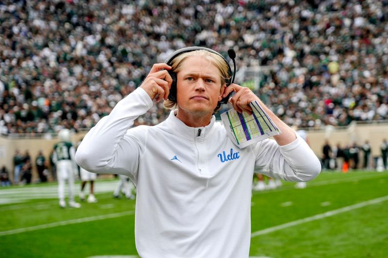 UCLA's assistant head coach Jerry Neuheisel adjusts his headset during the third quarter in the game against Michigan State on Saturday, Oct. 11, 2025, at Spartan Stadium in East Lansing.