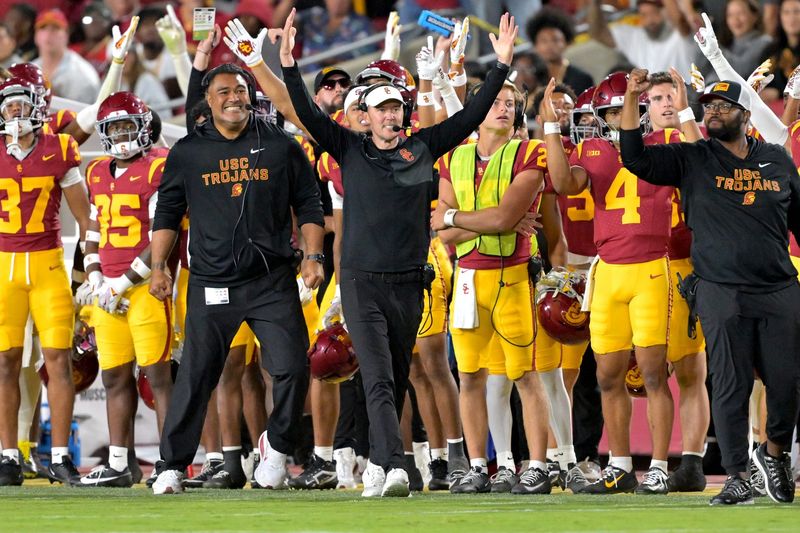 Oct 11, 2025; Los Angeles, California, USA; USC Trojans head coach Lincoln Riley (wearing white visor) celebrates along with defensive end coach Shaun Nua after kicker Ryon Sayeri (48) hit a 54-yard field goal in the second half against the Michigan Wolverines at United Airlines Field at the Los Angeles Memorial Coliseum. Mandatory Credit: Jayne Kamin-Oncea-Imagn Images