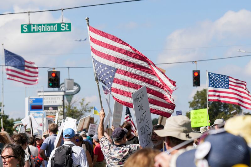 A demonstrator holds an American flag upside down, a symbol of America in distress, as they take part in the “No Kings: Memphis Resistance Fest” around the intersection of Poplar Avenue and Highland Street in Memphis, Tenn., on October 18, 2025.
