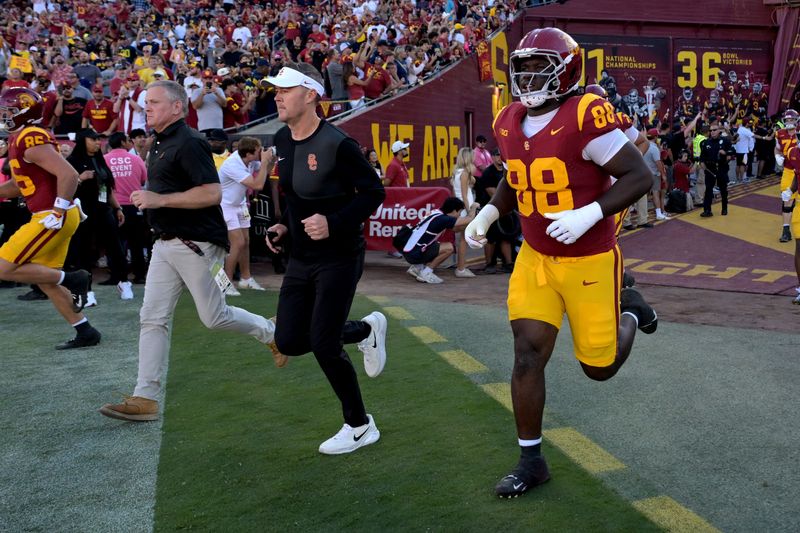 Oct 11, 2025; Los Angeles, California, USA; USC Trojans head coach Lincoln Riley, center, runs on to the field for the game against the Michigan Wolverines at United Airlines Field at the Los Angeles Memorial Coliseum. Mandatory Credit: Jayne Kamin-Oncea-Imagn Images