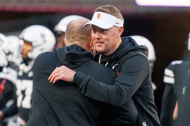 Nov 1, 2025; Lincoln, Nebraska, USA; Southern California Trojans head coach Lincoln Riley and Nebraska Cornhuskers head coach Matt Rhule embrace before the game at Memorial Stadium. Mandatory Credit: Dylan Widger-Imagn Images