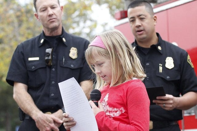 In this December 2014 file photo, Ventura Fire Department Chief David Endaya, right, and Battalion Chief Matt Brock listen to Ireland Sinklier, then a Sunset School fourth-grader read her winning essay.
