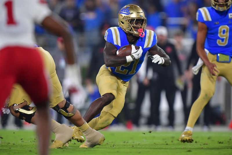 Nov 8, 2025; Pasadena, California, USA; UCLA Bruins running back Jaivian Thomas (21) runs the ball against the Nebraska Cornhuskers during the first half at the Rose Bowl. Mandatory Credit: Gary A. Vasquez-Imagn Images