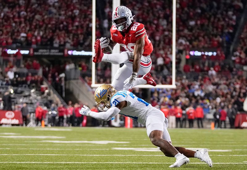 Ohio State Buckeyes running back James Peoples (20) hurdles UCLA Bruins defensive back Cole Martin (21) on his way to scoring a touchdown during the NCAA football game at Ohio Stadium in Columbus on Nov. 15, 2025.
