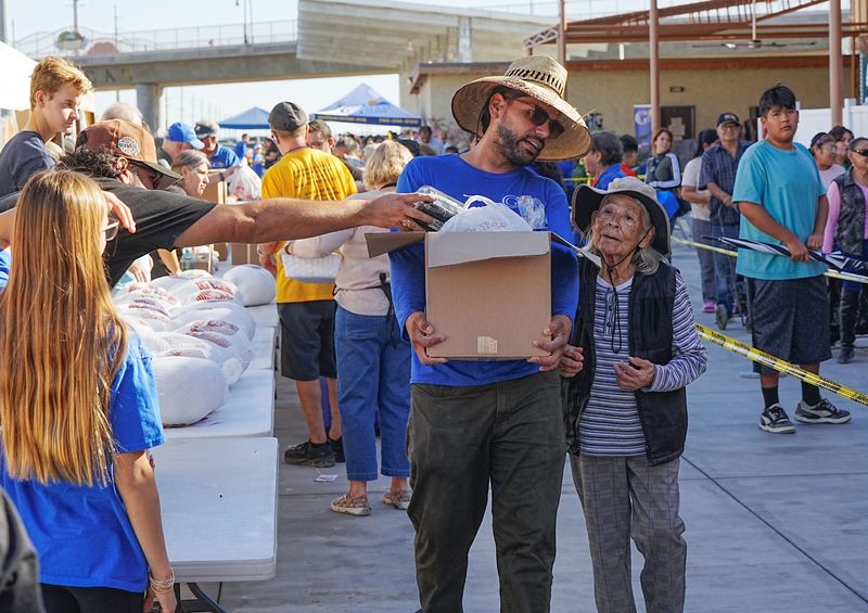 Volunteers help carry large boxes of food for the recipients of those meals during a holiday meal distribution event at the Galilee Center in Mecca, Calif., Nov. 26, 2025.